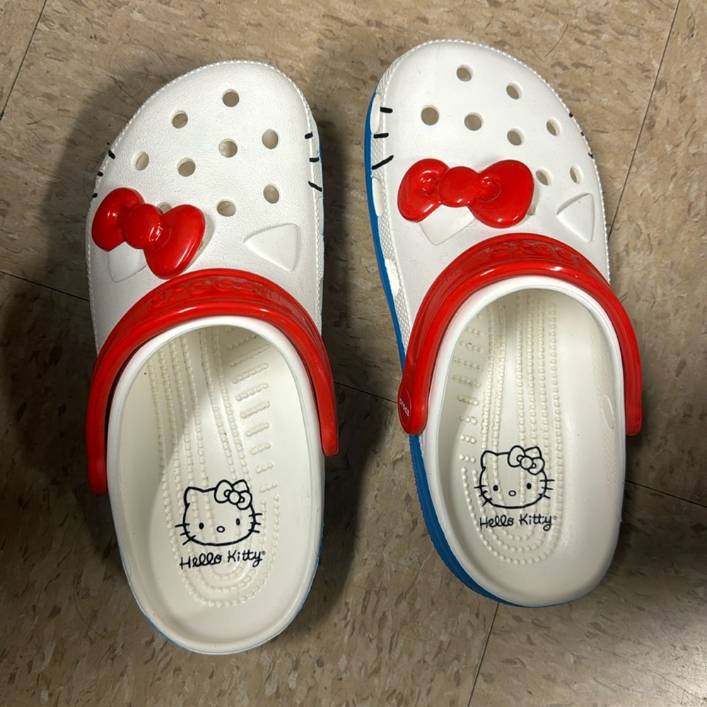 Gently used Hello Kitty Crocs. They are white with a red bow and blue trim.